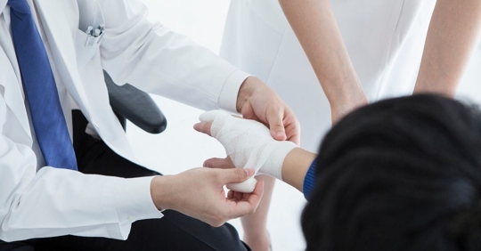 doctor wrapping a person's right hand in gauze
