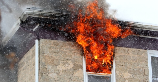 fire and soot exiting a window of an apartment building