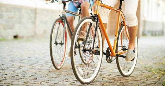 two people on bicycles riding on a cobblestone street