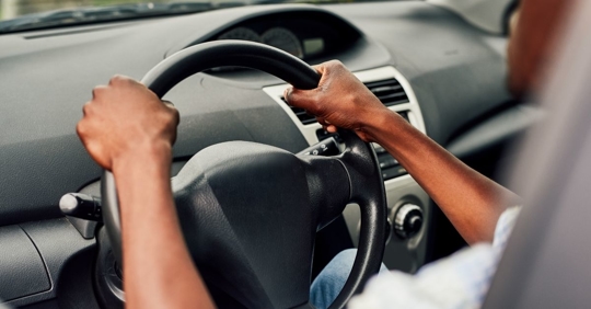 person with two hands on a steering wheel