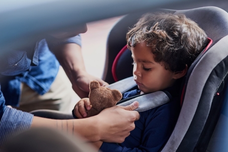 dad buckling toddler in car seat